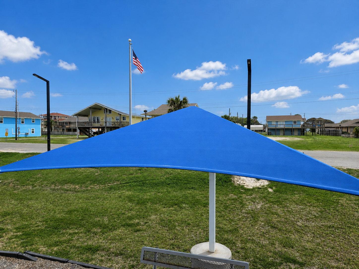 Royal blue triangle shade sail canopy at a coastal park near Corpus Christi, Texas — hurricane-conscious tension shade structure
