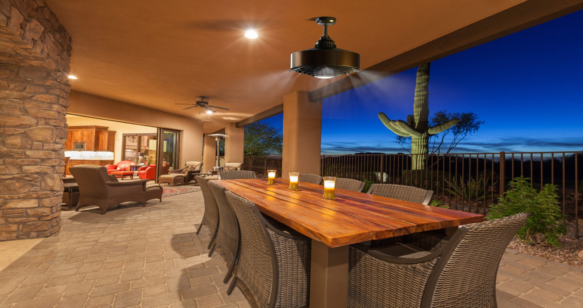 Ceiling-mounted misting fan running over a covered outdoor dining table at dusk