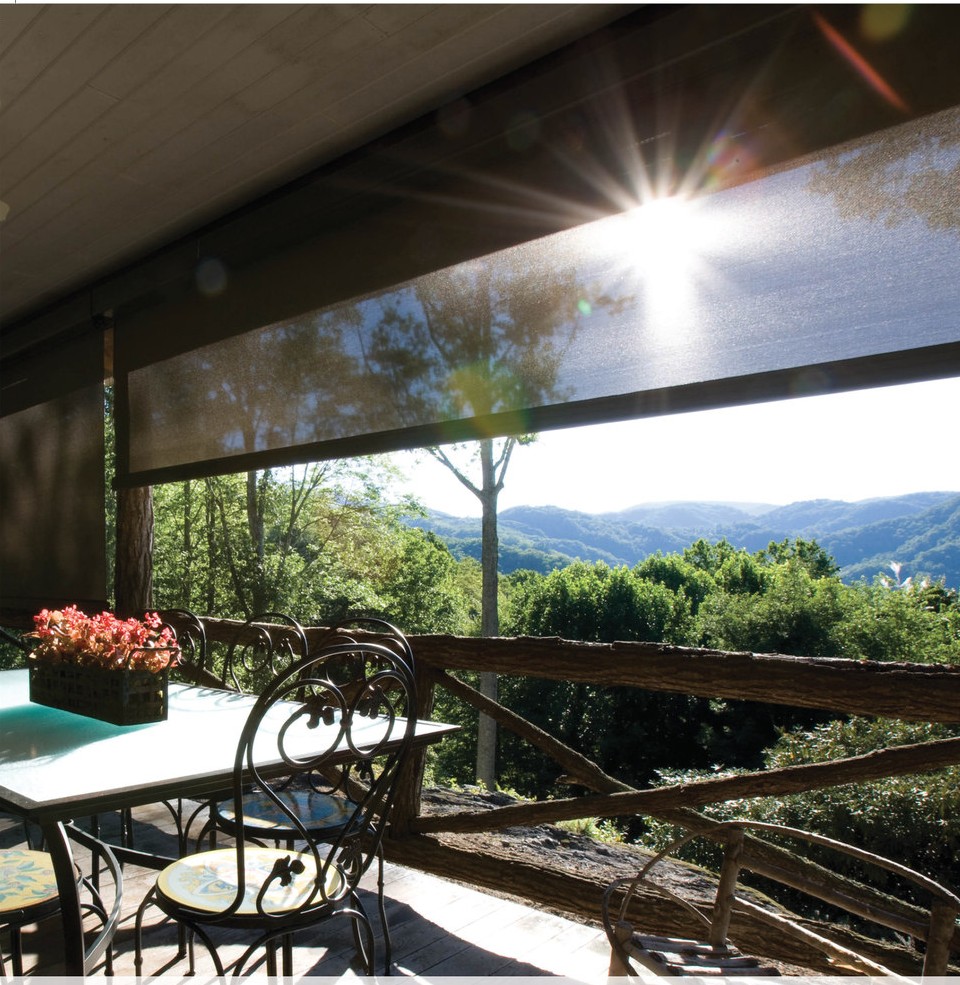 Solair® Power Screen partially lowered on a hillside porch, cutting late-afternoon sun glare over a Hill Country view