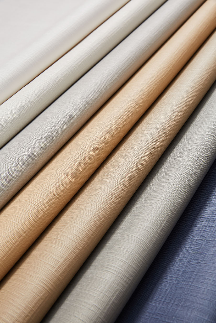 Rolls of Sunbrella® solution-dyed acrylic fabric in neutral, tan and blue tones