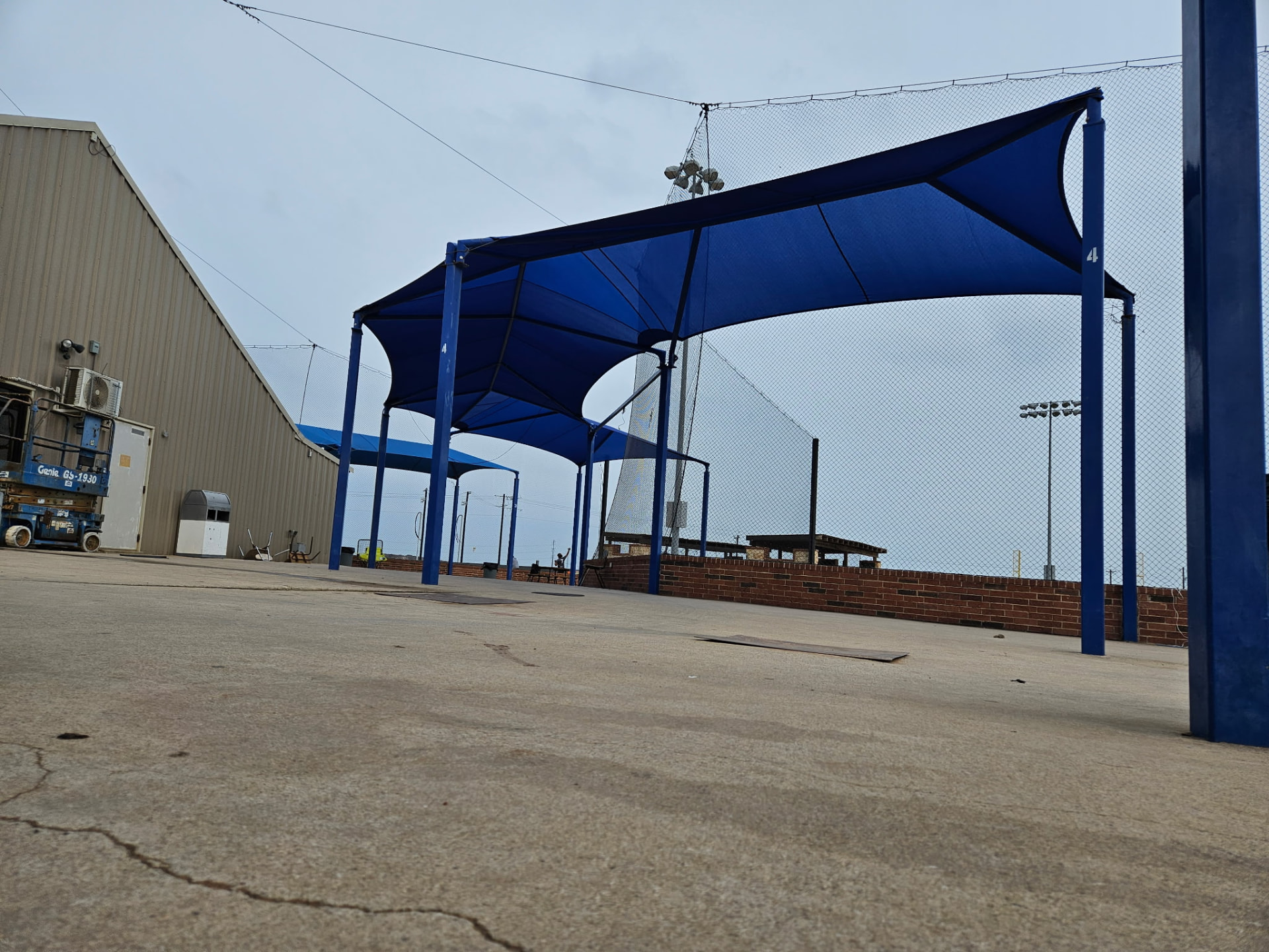 Royal blue hip-end shade canopy tension structure over a ballfield concourse in Seguin, Texas