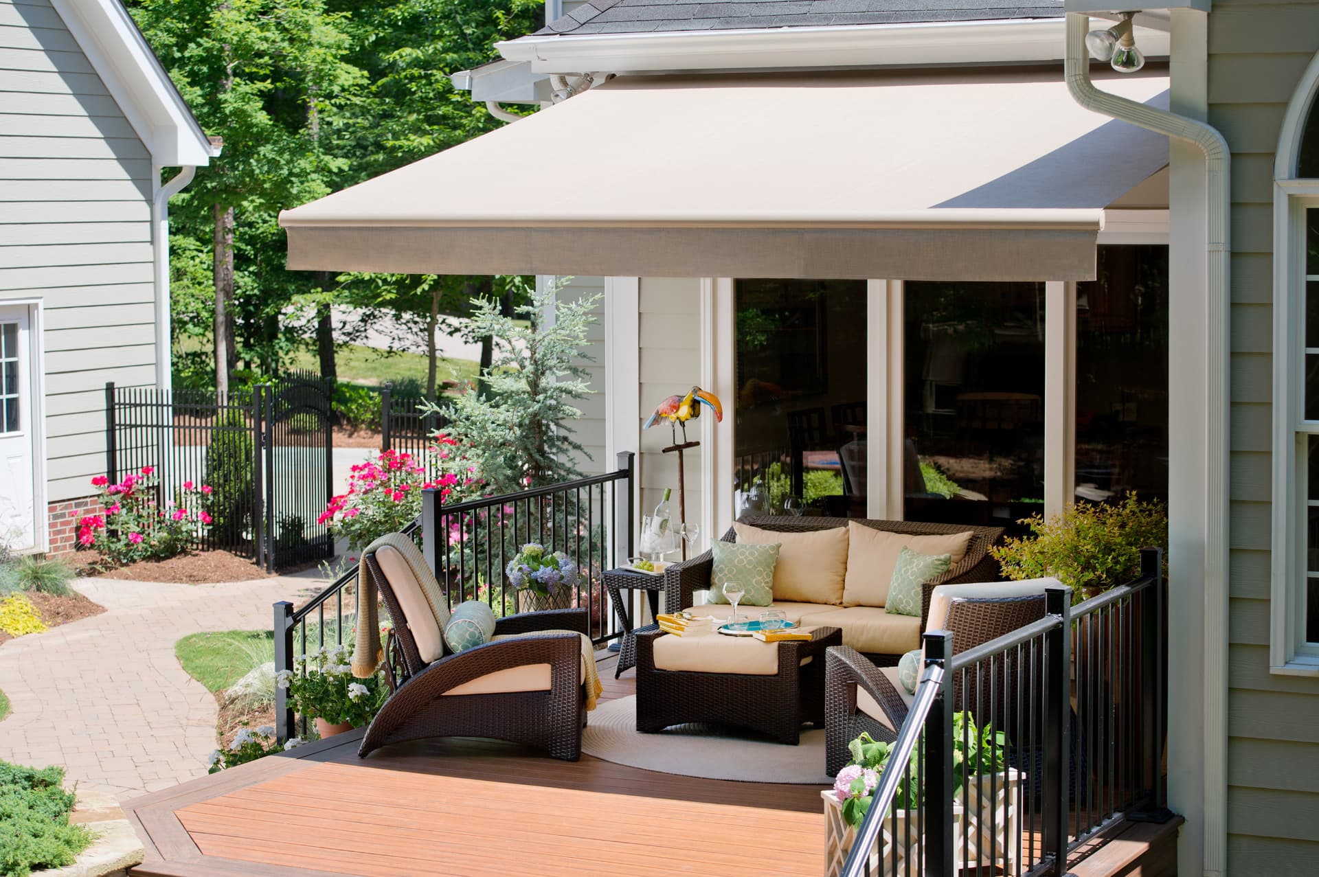 Motorized retractable awning extended over a residential back deck with wicker patio furniture, shading the seating area from afternoon sun