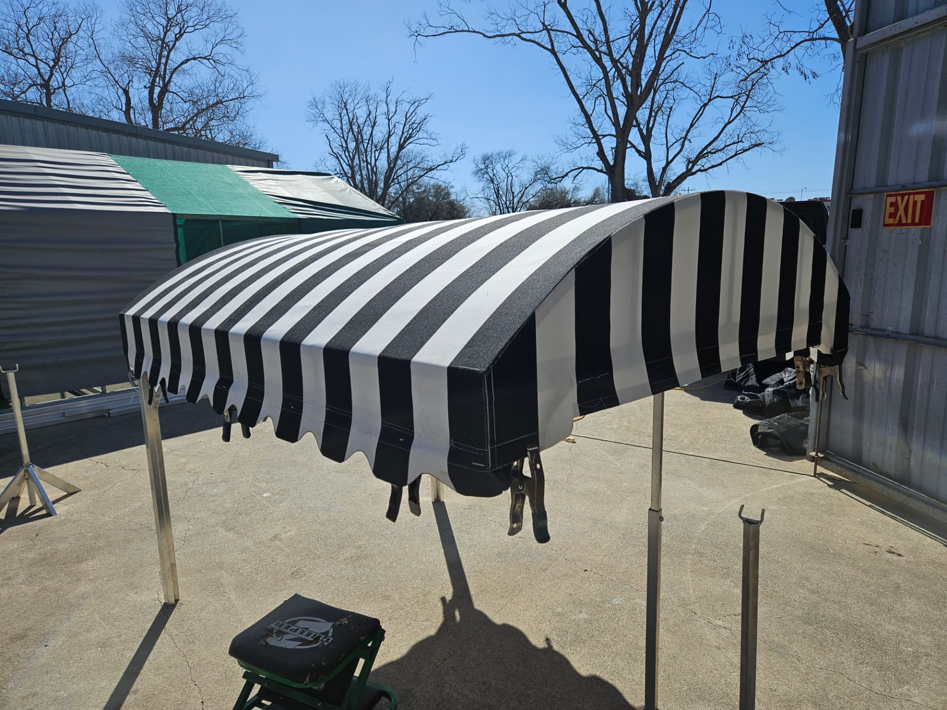 Black and white striped Sunbrella radius awning with scalloped valance built in the Texas Made Shade Seguin shop