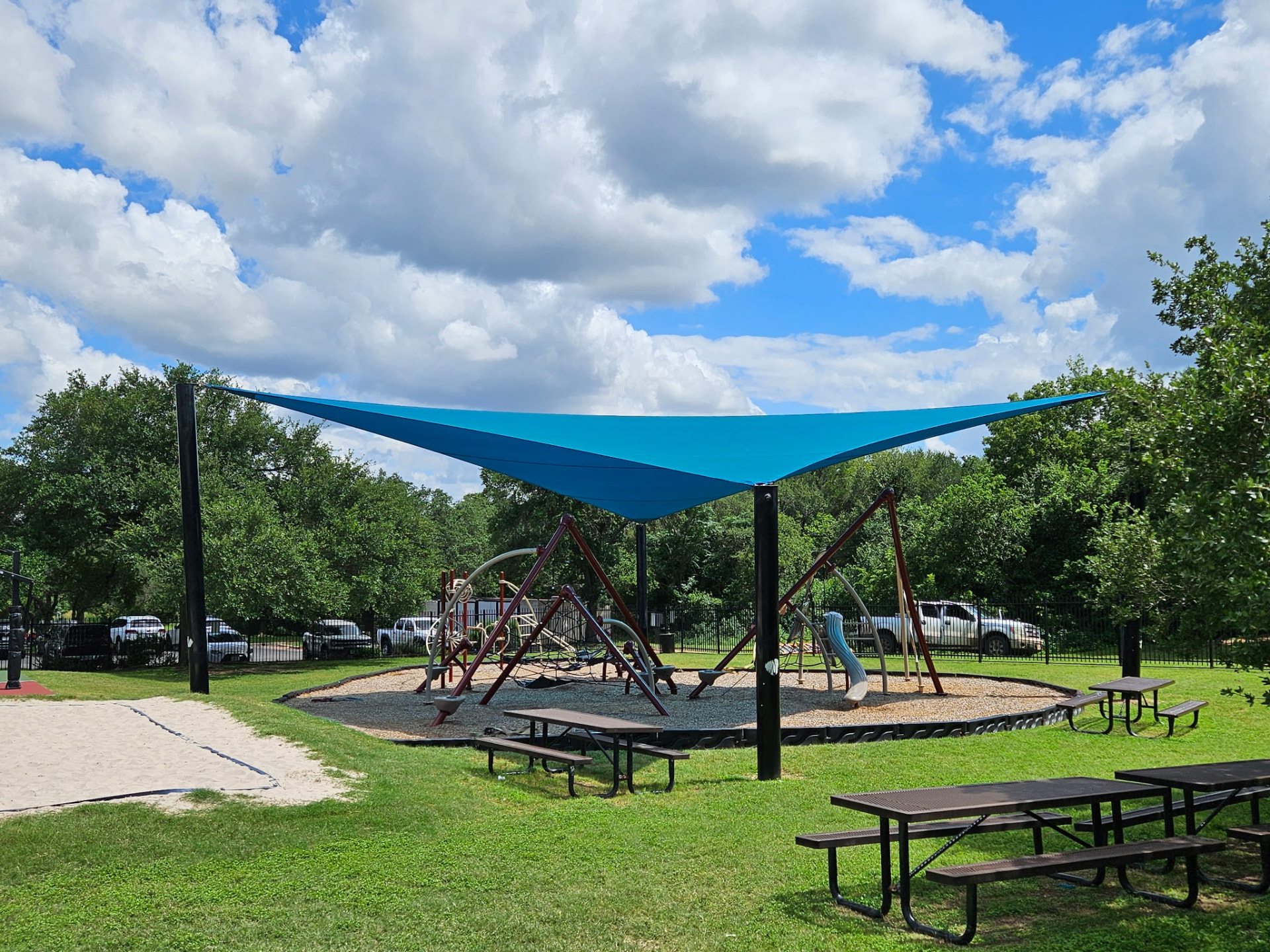 Triangle tension shade sail over a park playground and picnic area in Austin, Texas — custom shade sail fabricated locally