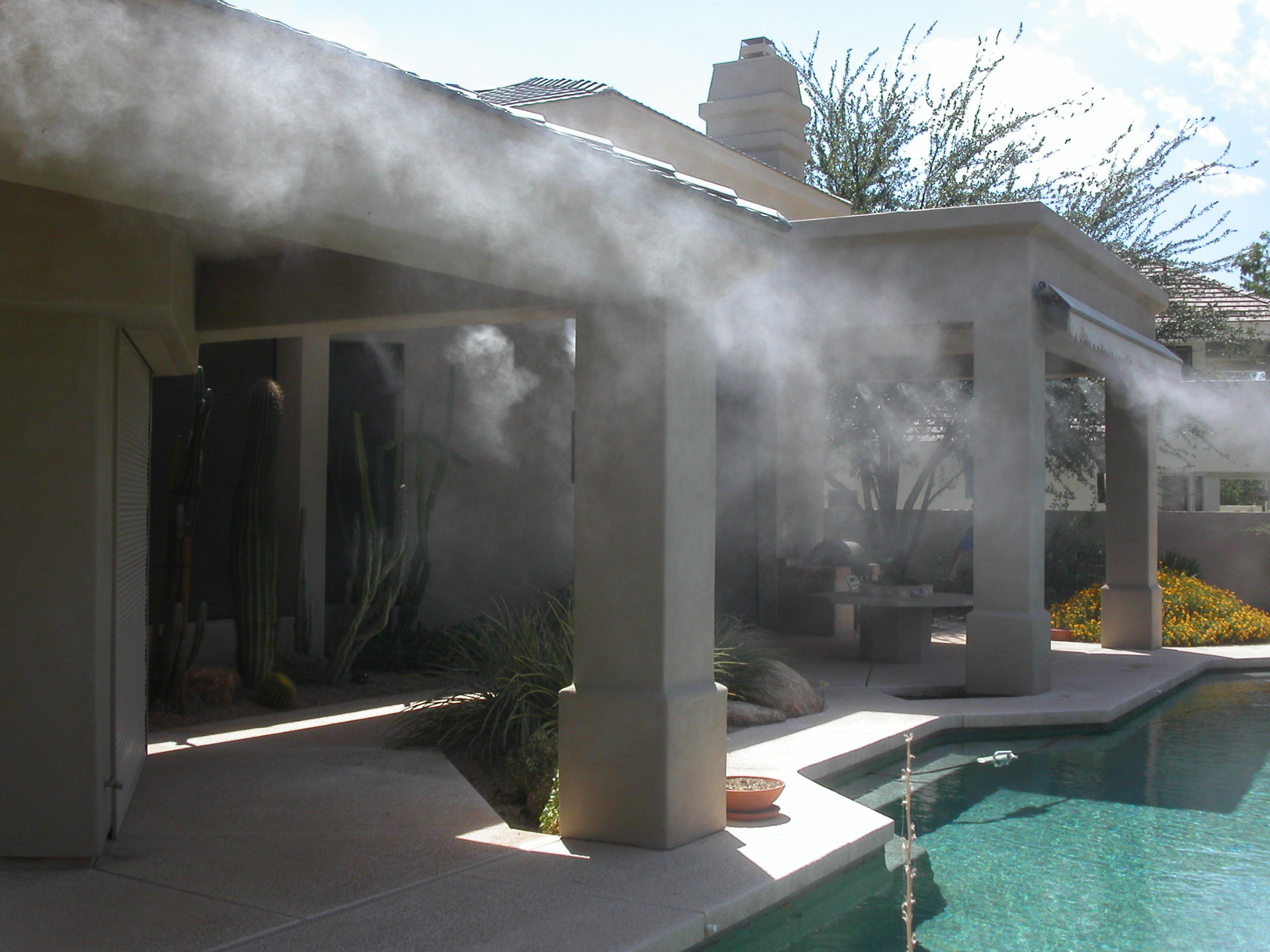 High-pressure patio misting system cooling a covered poolside patio and outdoor kitchen in San Antonio, Texas