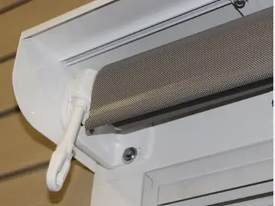 Manual gear crank operation and winding brace eye on a Solair® Vertical Curtain, the standard hand-crank mechanism for raising and lowering the shade