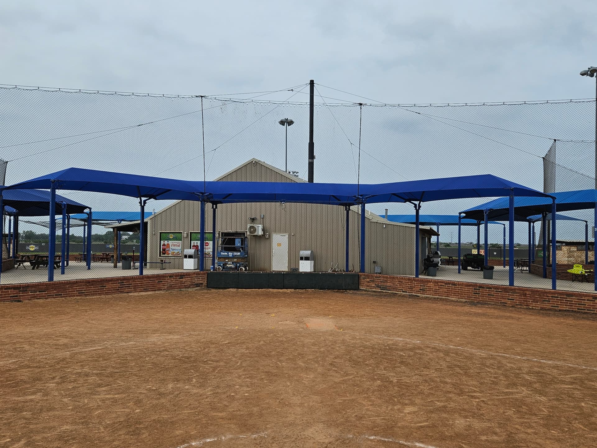 Multi-bay royal blue spectator shade canopies over the concession concourse at a baseball complex in Seguin, Texas