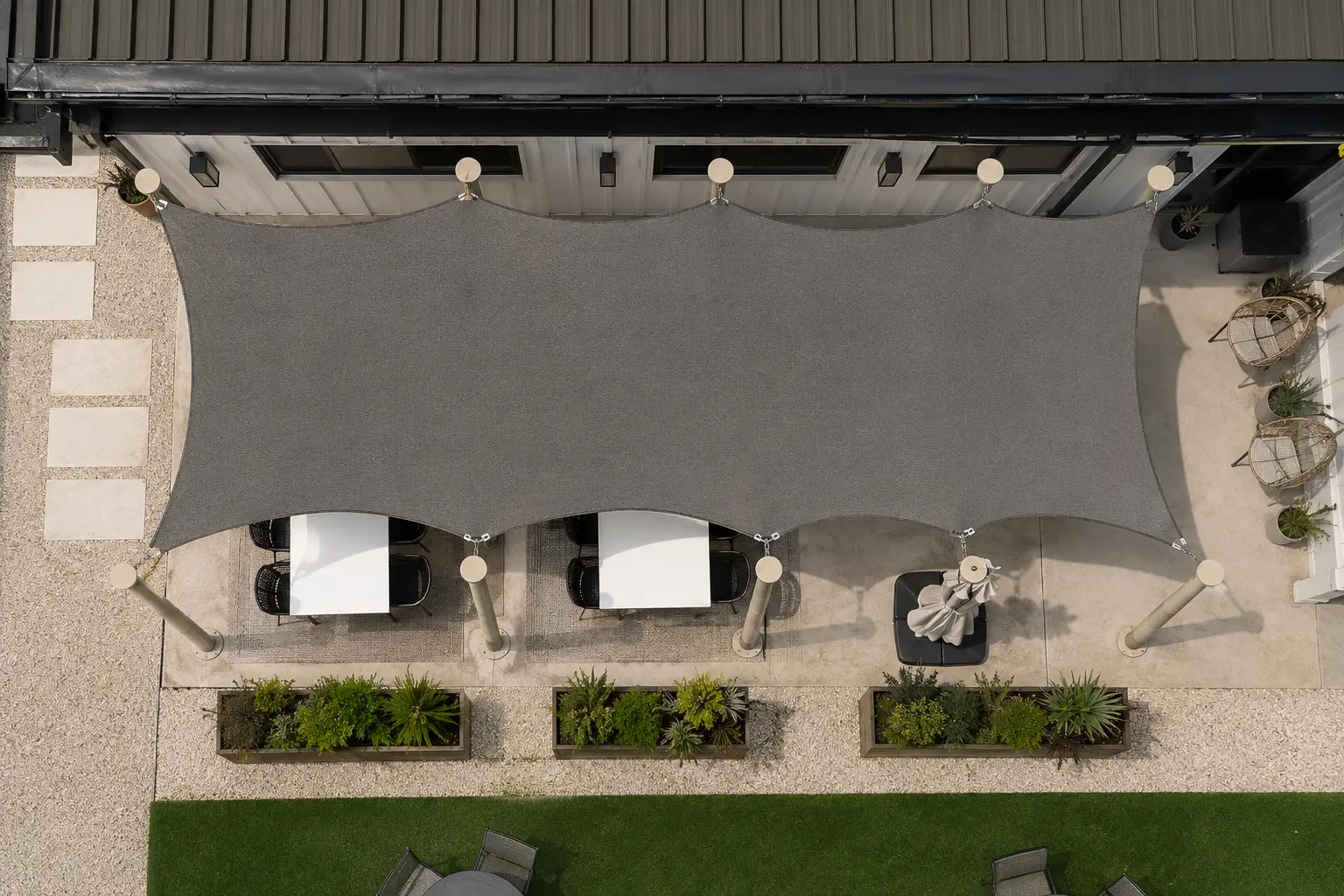 Overhead view of a charcoal tensioned shade sail canopy over a patio dining area in Austin, Texas — custom tension shade structure