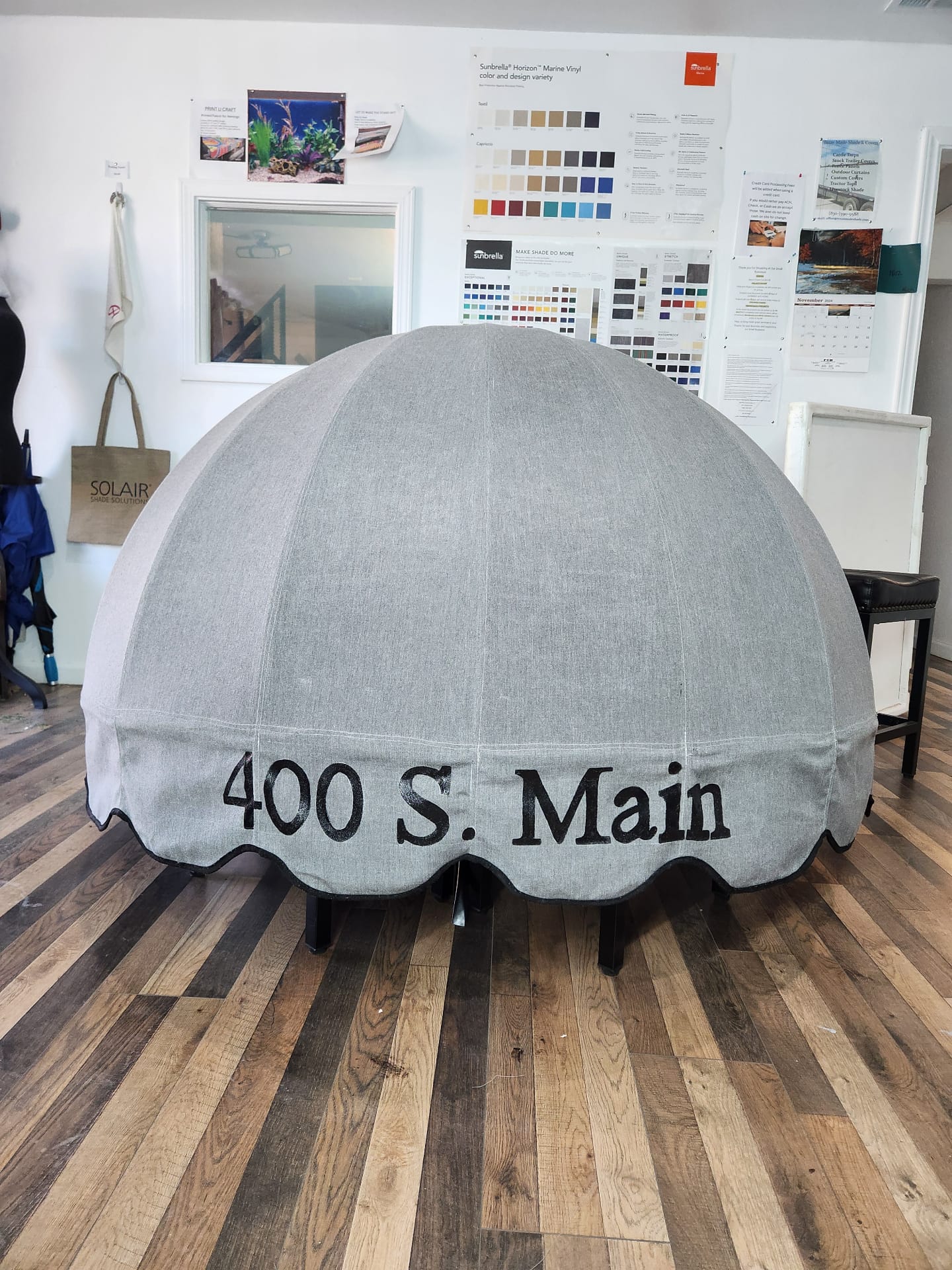 Custom grey Sunbrella half-dome entry awning with hand-painted black '400 S. Main' lettering, fabricated in the Texas Made Shade Seguin canvas shop before install