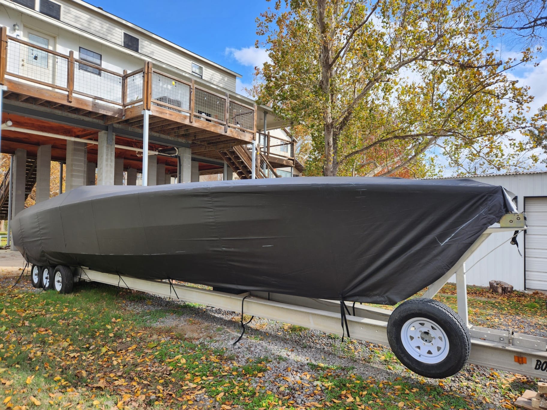 Custom black Sunbrella Marine full mooring cover by Texas Made Shade tied down over an offshore boat under a Texas Hill Country lakehouse deck