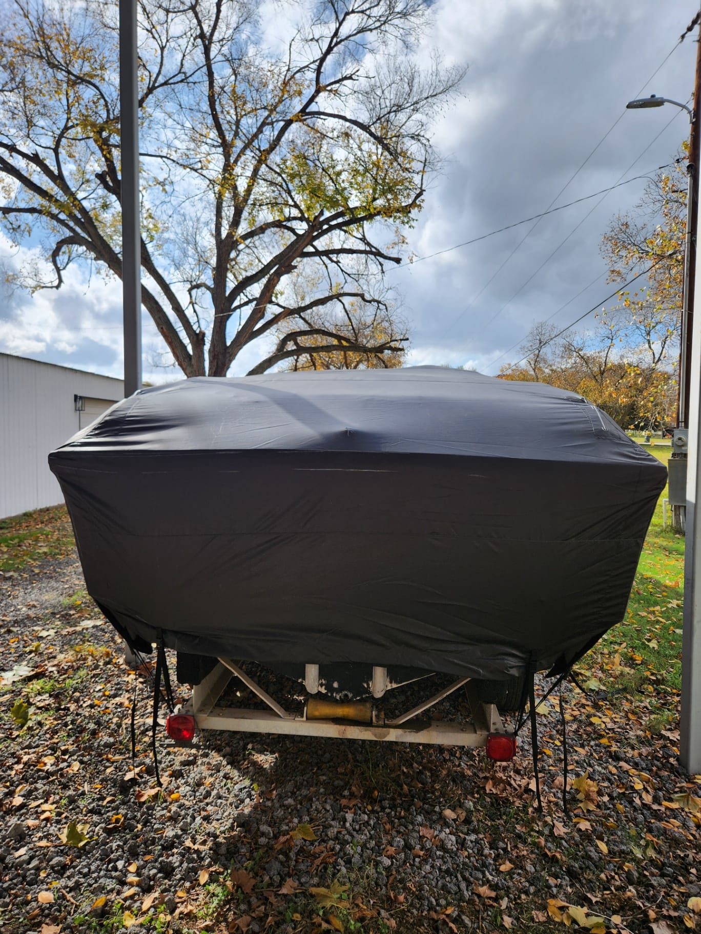 Rear-elevation view of a custom black marine canvas full storage cover fabricated by Texas Made Shade, sealed tight over the transom and outboards of an offshore boat on its trailer