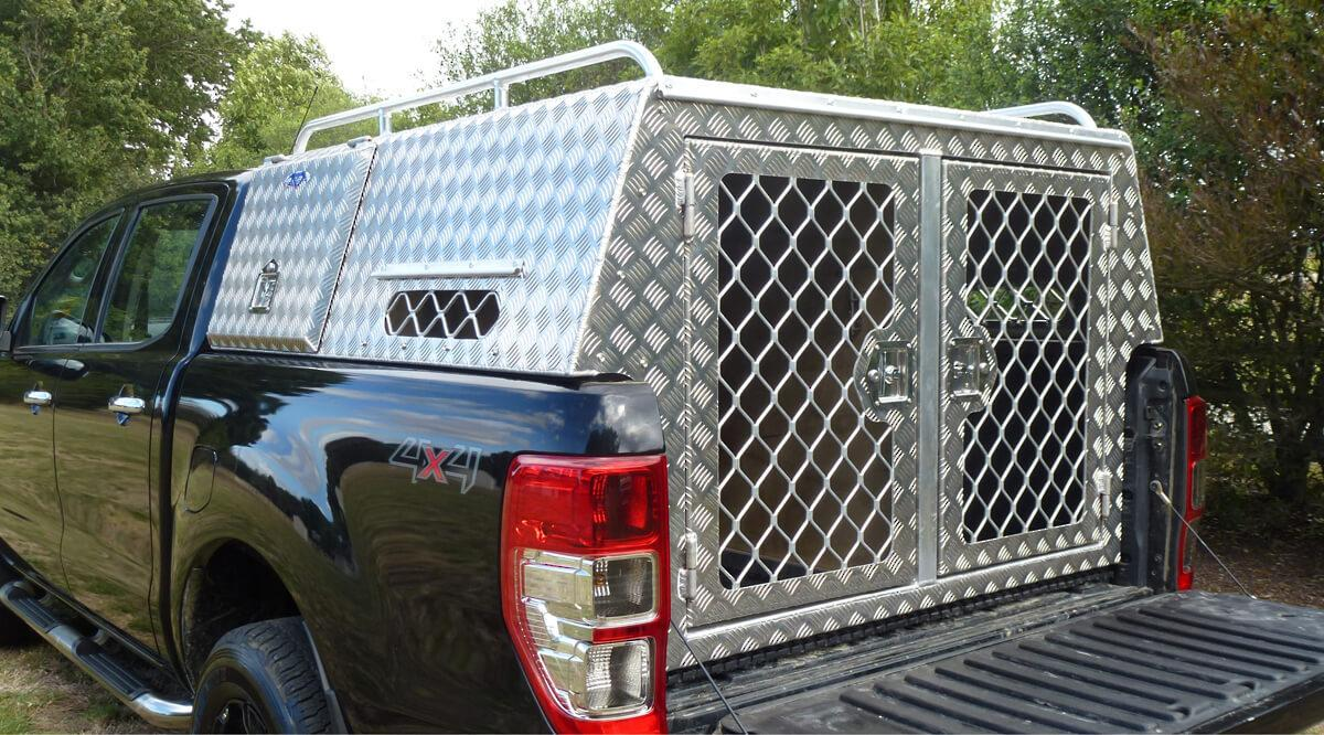 Custom welded diamond plate aluminum dog box on a 4x4 hunting truck — twin vented kennel doors with diamond mesh, side vent, roof rack and top storage lid — built by Texas Made Shade in Seguin, TX