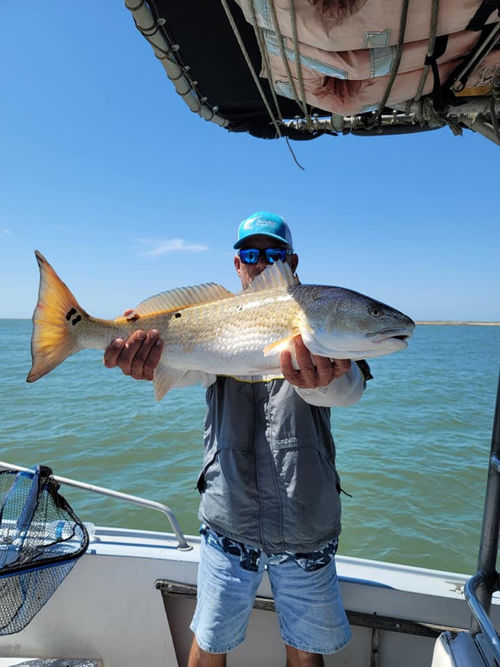 Angler holding a redfish under a custom canvas T-top on a Texas bay boat