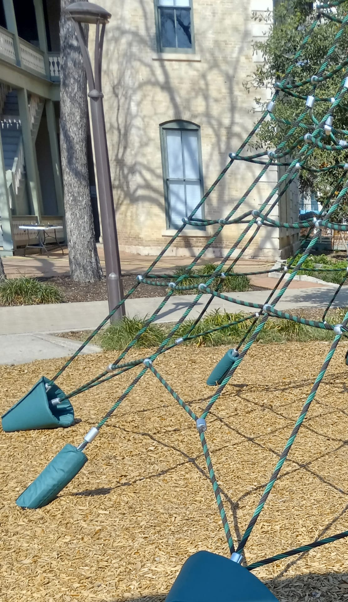 Custom teal Serge Ferrari padded anchor covers on playground rope-climber web structure