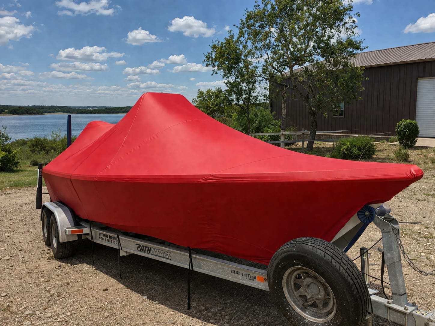 Custom red Sunbrella marine canvas full storage cover by Texas Made Shade fitted tight over a Pathfinder bay boat on its trailer at a Texas lake