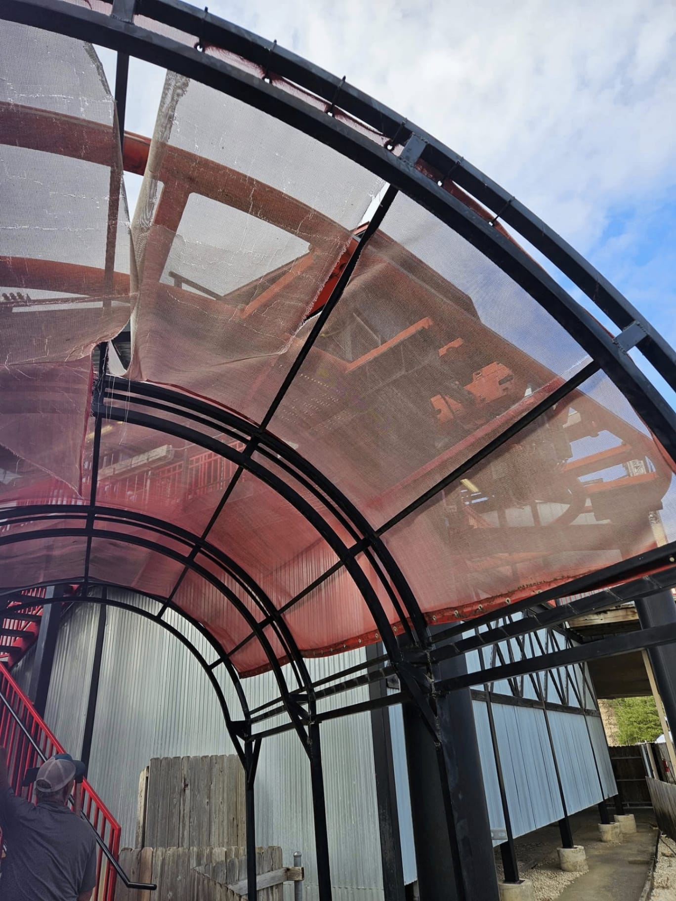 Faded red sail shade fabric on existing steel frame in a South Texas backyard before re-cover
