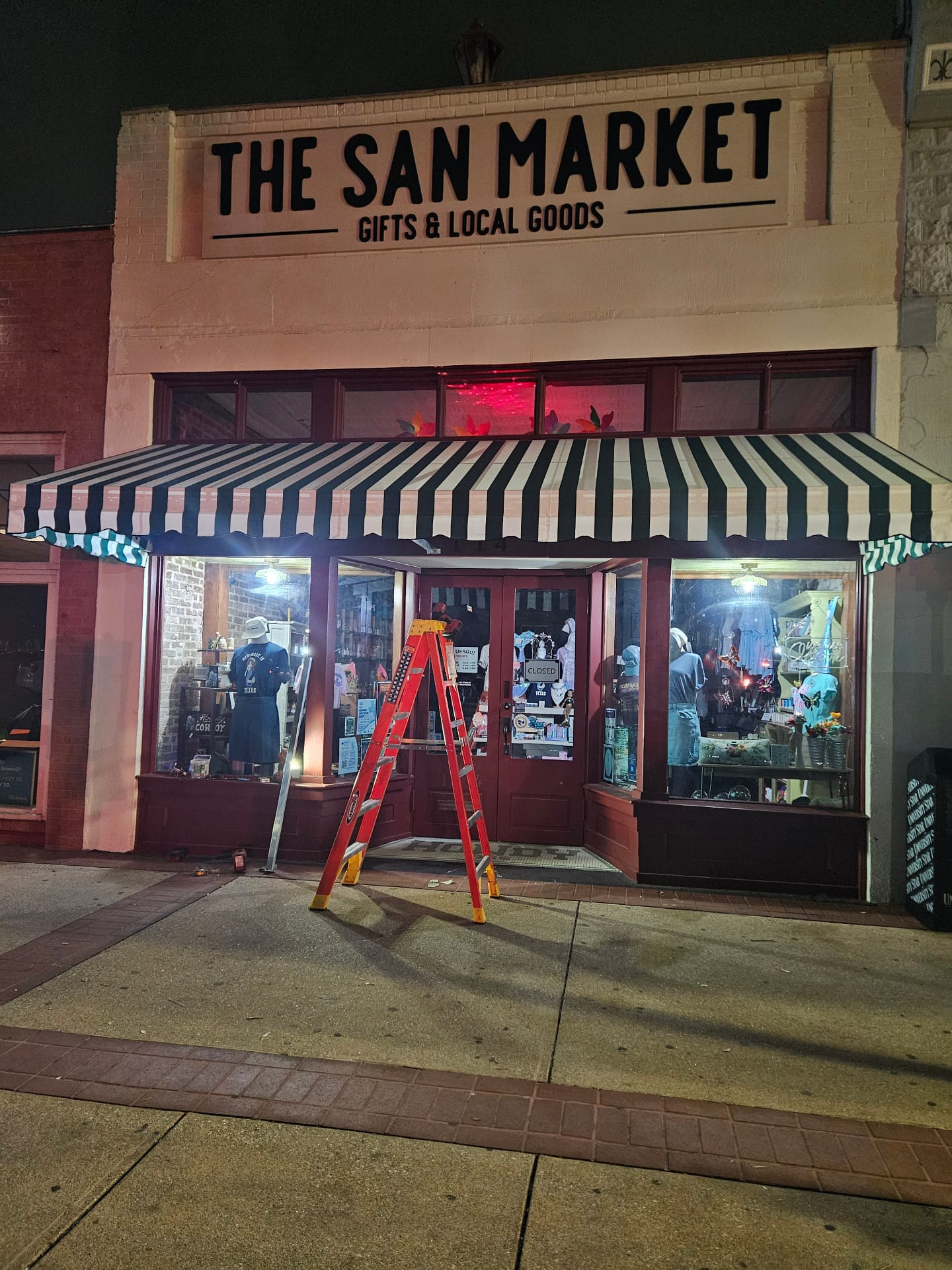 The San Market green-and-white striped storefront awning installed by Texas Made Shade in downtown San Marcos at night