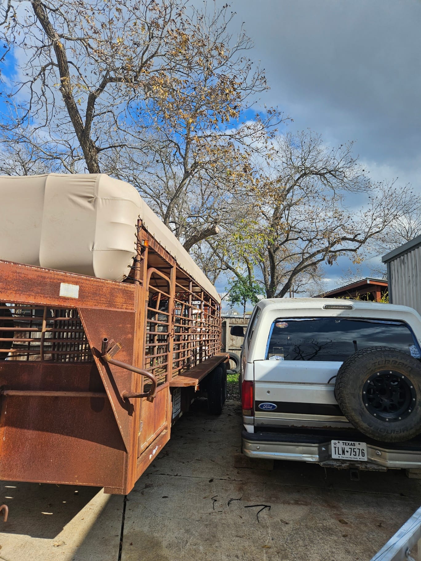 Tan heavy-duty vinyl top cover patterned and installed on a vintage rust-patina gooseneck cattle trailer in Seguin, TX