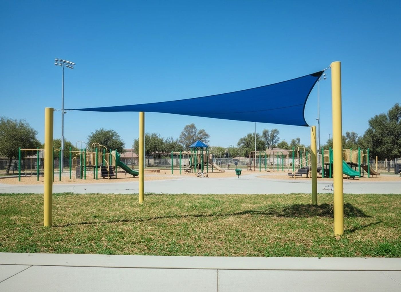 Blue shade sail tension structure over playground