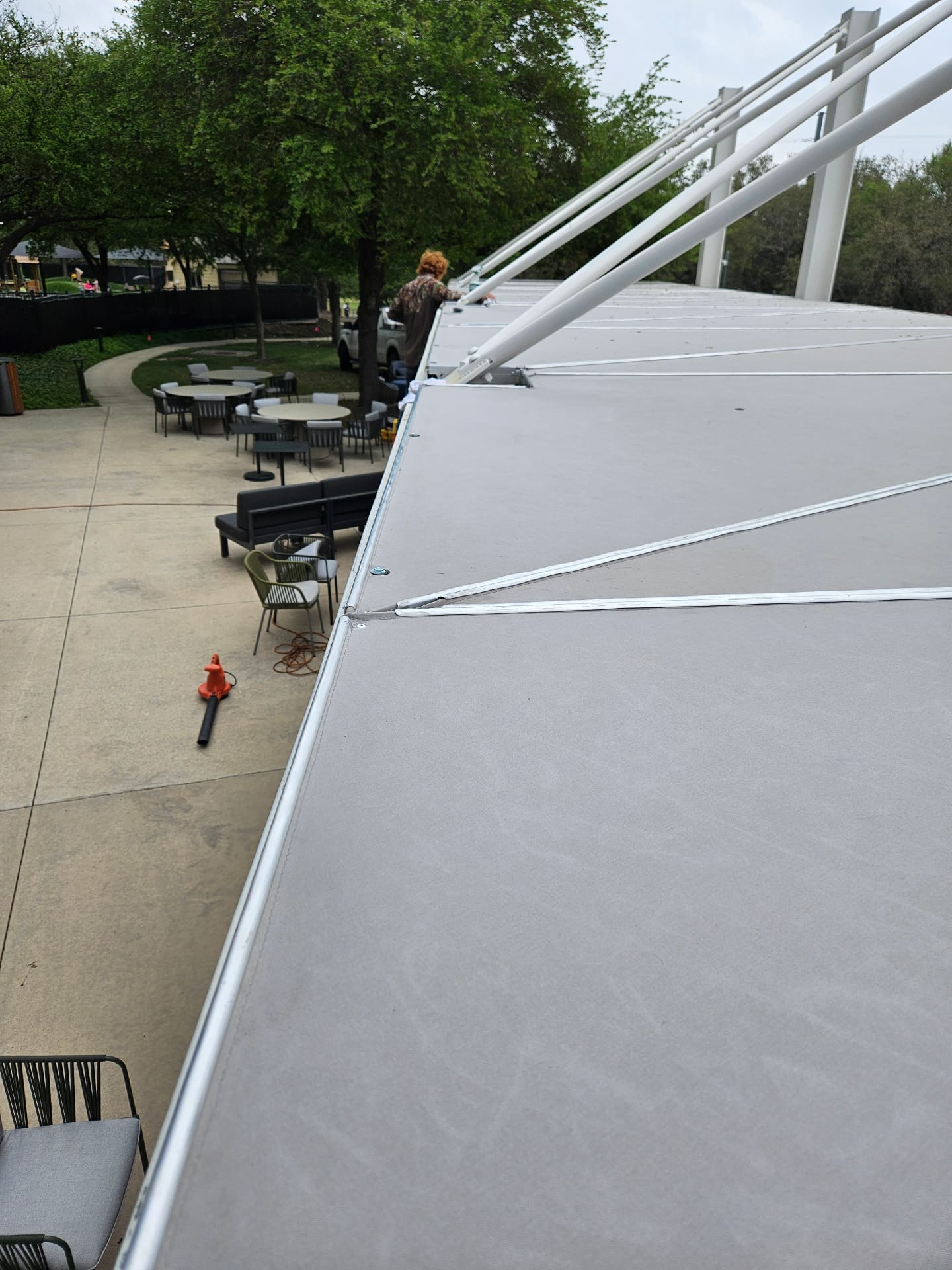 Aerial view of a custom-welded aluminum canopy frame with tensioned canvas panels over a corporate patio in Texas, showing TIG-welded trusses and gussets